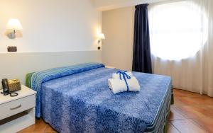 a hotel room with a bed with a blue blanket at Le Tartarughe Aparthotel in Letojanni