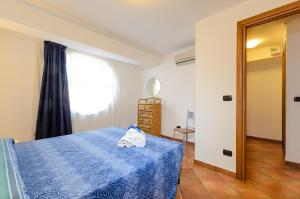 a bedroom with a blue bed and a window at Le Tartarughe Aparthotel in Letojanni