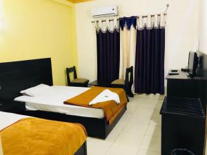 a hotel room with two beds and a television at Hotel Joshi in Bhairāhawā