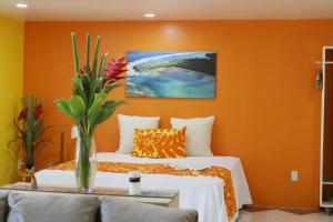 a bedroom with orange walls and a bed with a vase of flowers at ShineAwayHomes - Mountain View AIR CONDITIONED in Rarotonga