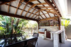 an outdoor kitchen with a table and chairs on a patio at THE BOARDWALK Relaxing Beachside Family Entertainer in Marcoola