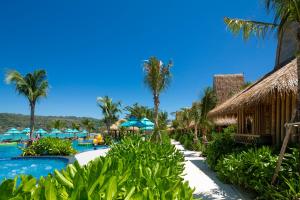 a resort with a pool and palm trees and umbrellas at Phi Phi CoCo Beach Resort in Phi Phi Islands