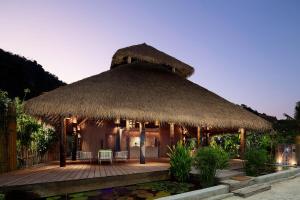 a hut with a straw roof with chairs and a pond at Phi Phi CoCo Beach Resort in Phi Phi Islands