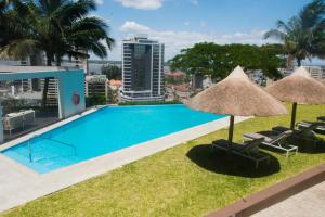 una piscina con 2 sombrillas y algunas sillas en Montebelo Girassol Maputo Hotel, en Maputo