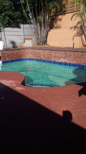 a swimming pool in a yard with a brick wall at DYNA GUEST HOUSE in Durban