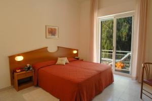 a bedroom with a red bed and a window at Hotel Helios in Diano Marina