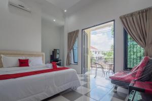 占碑市RedDoorz near Sultan Thaha Airport Jambi的一间带一张床和一把椅子的卧室以及一个阳台