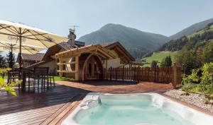 a hot tub on a deck next to a house at Gitschberg - Appartements in Vandoies