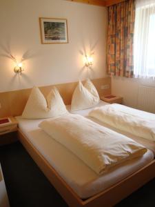 1 Schlafzimmer mit 2 Betten mit weißer Bettwäsche und Kissen in der Unterkunft Haus Zirmblick in Saalbach-Hinterglemm