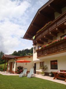eine Terrasse mit Stühlen, einem Sonnenschirm und einem Gebäude in der Unterkunft Haus Zirmblick in Saalbach-Hinterglemm
