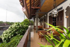 eine Veranda mit Bänken und Blumen auf einem Gebäude in der Unterkunft Rumah Roda in Ubud