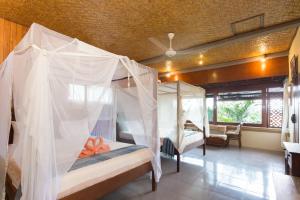 Schlafzimmer mit 4 Betten und Moskitonetzen in der Unterkunft Rumah Roda in Ubud