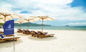 a group of chairs and umbrellas on a beach at Boton Blue Hotel & Spa in Nha Trang