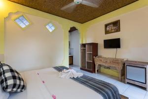 ein Schlafzimmer mit einem Bett, einem Schreibtisch und einem Fernseher in der Unterkunft Rumah Roda in Ubud
