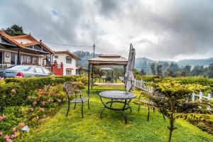 uma mesa e cadeiras e um guarda-sol num quintal em FabEscape Saint Clouds em Ooty