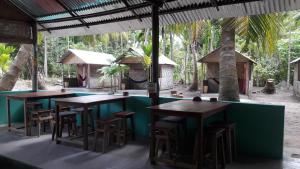 um restaurante com mesas e bancos em frente a uma piscina em Elephant and Four wise men resort em Neil Island