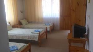 a small room with two beds and a television at Svetla Guest House in Primorsko