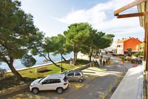 two cars parked in a parking lot next to the water at Apartman Petra in Fažana