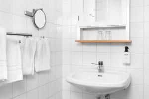 a white bathroom with a sink and a mirror at Hotell Stenugnen in Visby