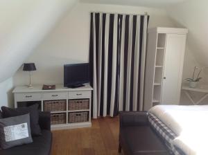 ein Schlafzimmer mit einem Bett, einem TV und einem Sofa in der Unterkunft Wellness Caracol in West-Terschelling