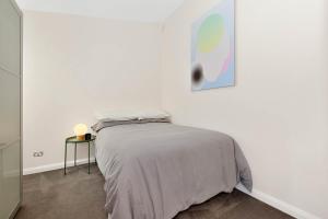 a white bedroom with a bed and a side table at Geelong West Miner's Cottage in Geelong