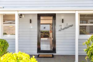 a white house with a black door on it at Geelong West Miner's Cottage in Geelong