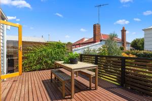 a wooden deck with a table and a bench at Geelong West Miner's Cottage in Geelong