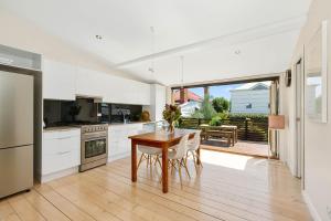 a kitchen with white cabinets and a wooden table at Geelong West Miner's Cottage in Geelong