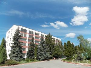 a white building with trees in front of a street at Dibrova in Bila Tserkva