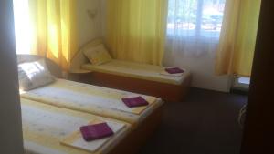 a room with three beds and a window with yellow curtains at Svetla Guest House in Primorsko