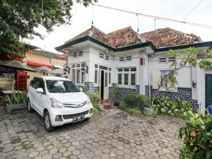 a white car parked in front of a white house at Reddoorz Syariah near Wijilan Yogyakarta in Yogyakarta