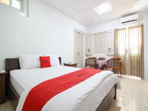 um quarto com uma cama grande com detalhes em vermelho em Reddoorz Syariah near Wijilan Yogyakarta em Yogyakarta