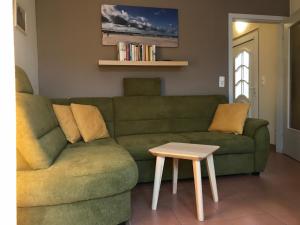 uma sala de estar com um sofá verde e uma mesa em Ferienwohnung-Strandspaziergang, kleine Wohnung em Börgerende-Rethwisch