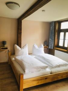 1 Schlafzimmer mit 2 Betten und weißen Kissen in der Unterkunft Ferienwohnungen an der Blasiikirche in Quedlinburg
