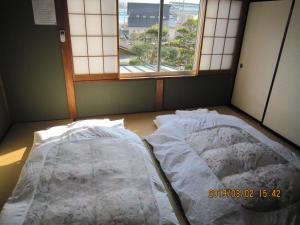 an empty bed in a room with a window at Minshuku Kobayashi in Narusawa
