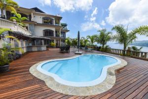 a swimming pool on a wooden deck next to a house at Ocean Terrace in Anse Royale