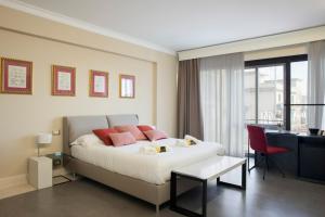 Schlafzimmer mit einem Bett mit rosa Kissen und einem Schreibtisch in der Unterkunft Principessa Mafalda in Messina