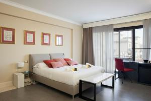 a bedroom with a bed with pink pillows and a desk at Principessa Mafalda in Messina