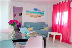 a living room with a blue couch and a glass table at Apartamento Del Rio Playa in Cádiz