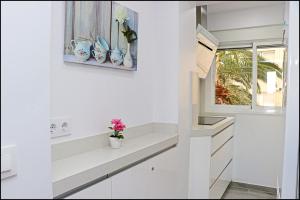 una cocina con armarios blancos y una ventana en Apartamento Del Rio Playa, en Cádiz