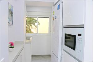 una cocina con armarios blancos y una ventana en Apartamento Del Rio Playa, en Cádiz