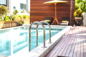 a swimming pool with metal railings next to a house at La Mai Hotel in Chiang Mai