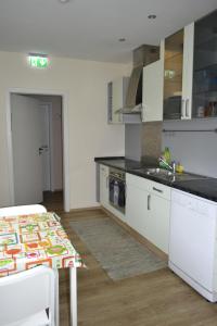 a kitchen with white cabinets and a table with a sink at Pension Highway Bünde in Bünde