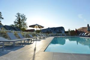 a swimming pool with lounge chairs and an umbrella at Hôtel-Spa Domaine de Diane in Quend
