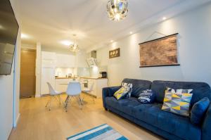 a living room with a blue couch and a kitchen at Fitness Apartment - Spa Sauna & Gym by Grand Apartments in Gdańsk