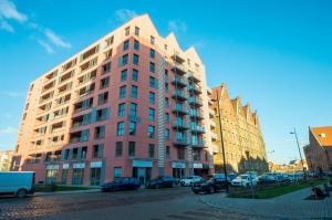 a tall building with cars parked in front of it at Fitness Apartment - Spa Sauna & Gym by Grand Apartments in Gdańsk