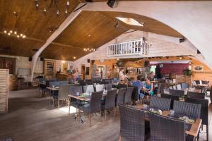 a restaurant with people sitting at tables and chairs at Hôtel-Spa Domaine de Diane in Quend