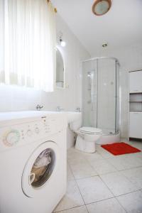 a white bathroom with a washing machine and a toilet at Large gardens 2 in Bibinje