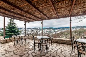 a patio with tables and chairs and a view of mountains at Guesthouse Selini in Vitsa