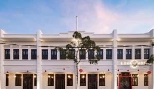 un edificio blanco con un árbol delante en Liu Men Melaka en Melaka